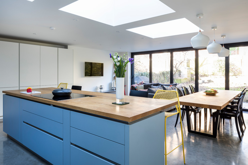 Moderne Küche mit blauen Schränken, Elektrogeräten mit Frontblende und Halbinsel in London