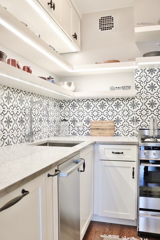 Exempel på ett litet klassiskt l-kök, med en undermonterad diskho, skåp i shakerstil, vita skåp, bänkskiva i kvarts, grått stänkskydd, stänkskydd i cementkakel, rostfria vitvaror, mellanmörkt trägolv och brunt golv