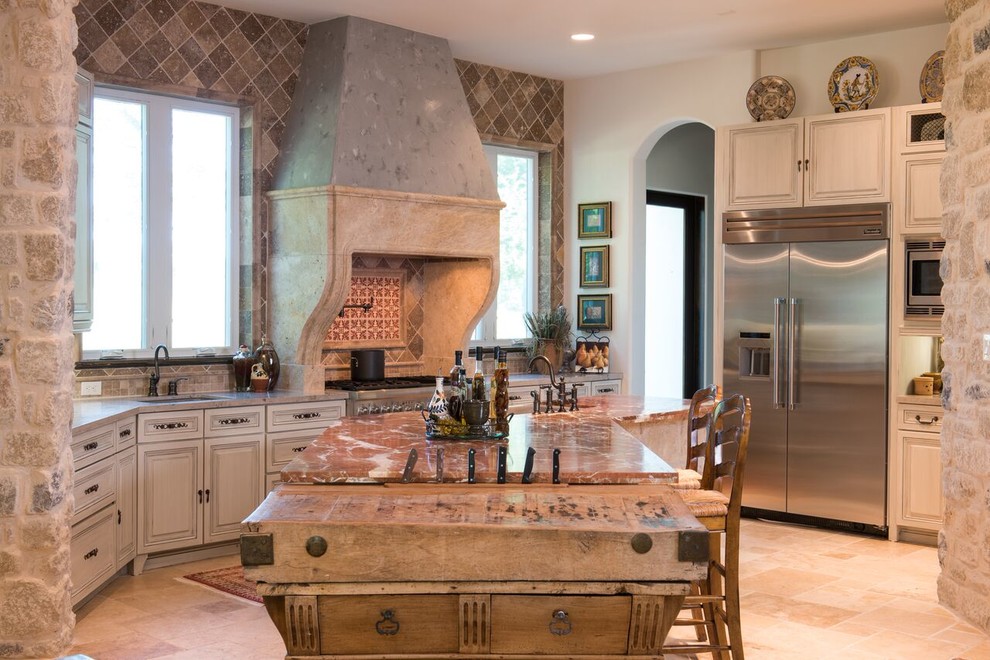 Inspiration for a large mediterranean u-shaped kitchen in Houston with a submerged sink, raised-panel cabinets, distressed cabinets, marble worktops, beige splashback, stone tiled splashback, stainless steel appliances, ceramic flooring and an island.