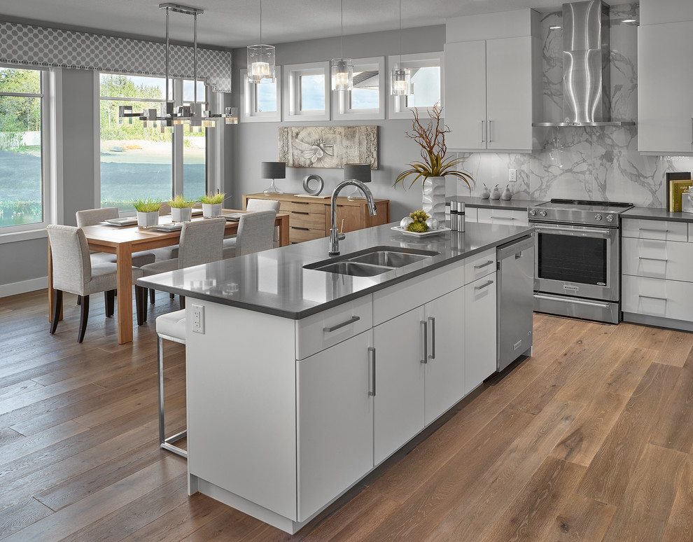 Inspiration for a large contemporary l-shaped medium tone wood floor open concept kitchen remodel in Edmonton with an undermount sink, flat-panel cabinets, white cabinets, quartz countertops, gray backsplash, ceramic backsplash, stainless steel appliances and an island