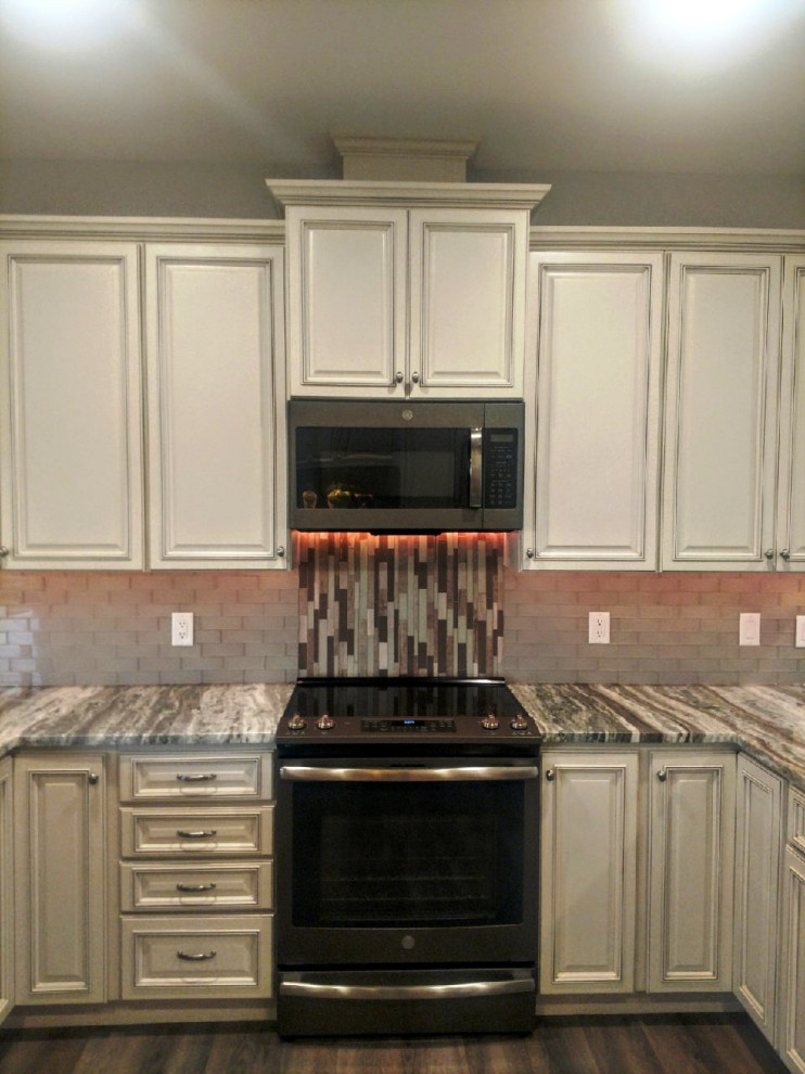 Inspiration for a mid-sized transitional u-shaped laminate floor and multicolored floor eat-in kitchen remodel in Other with an undermount sink, raised-panel cabinets, white cabinets, granite countertops, gray backsplash, glass tile backsplash, stainless steel appliances, a peninsula and multicolored countertops