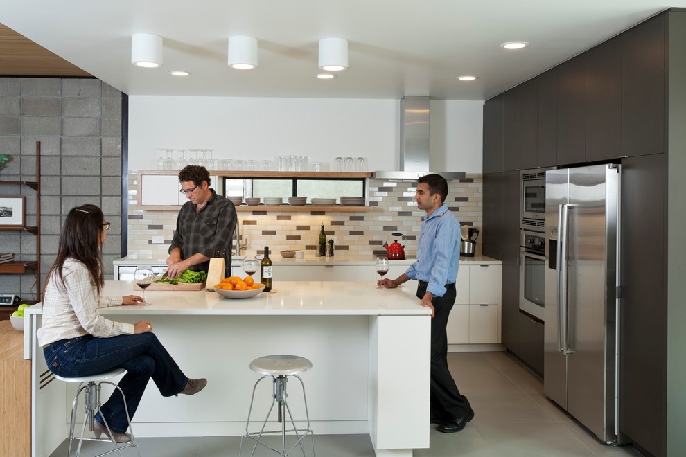 Aménagement d'une cuisine moderne en L et bois foncé avec un placard à porte plane, une crédence multicolore et un électroménager en acier inoxydable.