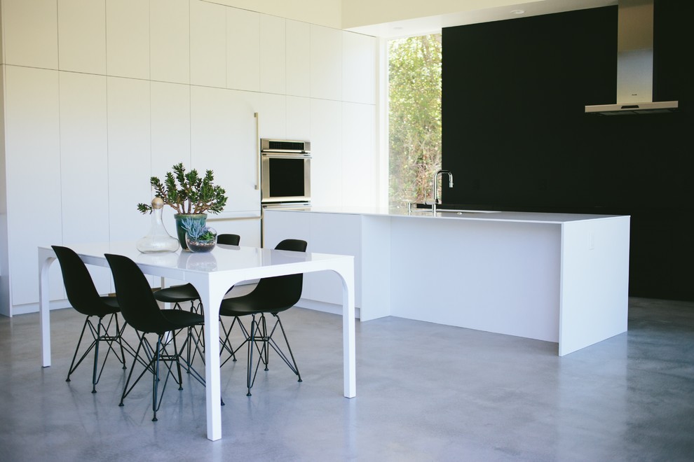 Esempio di una grande cucina moderna con lavello a vasca singola, ante lisce, ante bianche, top in superficie solida, paraspruzzi nero, elettrodomestici in acciaio inossidabile e pavimento in cemento