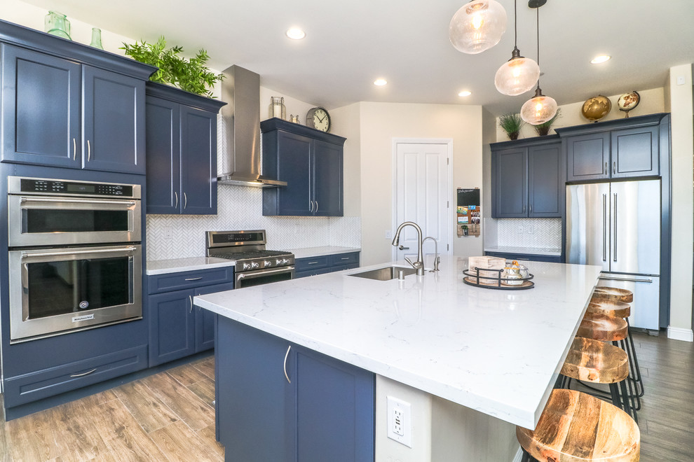 Exempel på ett mellanstort modernt vit vitt kök, med en köksö, en undermonterad diskho, luckor med infälld panel, blå skåp, bänkskiva i kvarts, vitt stänkskydd, rostfria vitvaror, brunt golv och klinkergolv i porslin