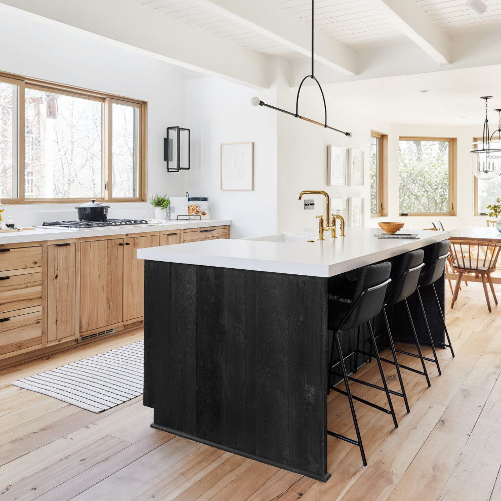 This is an example of a rustic kitchen/diner with engineered stone countertops, white splashback, an island, white worktops, light wood cabinets, light hardwood flooring and beige floors.