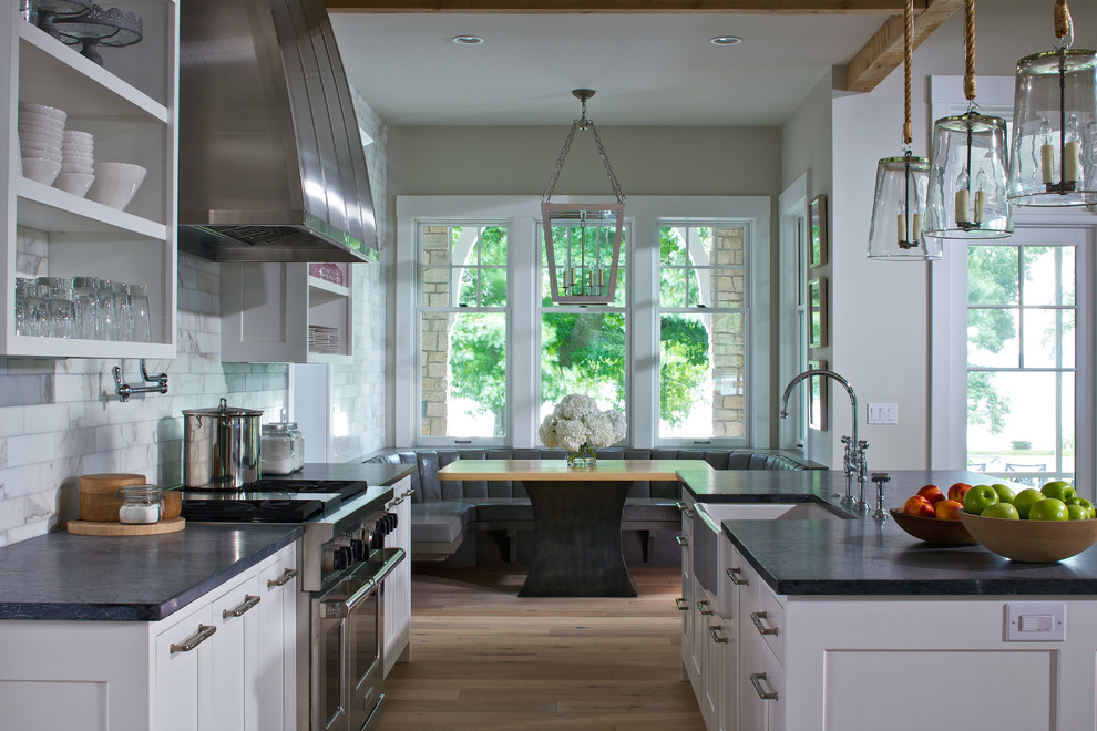 Eat-in kitchen - eclectic single-wall light wood floor eat-in kitchen idea in Grand Rapids with a farmhouse sink, white cabinets, soapstone countertops, white backsplash, porcelain backsplash, stainless steel appliances and an island