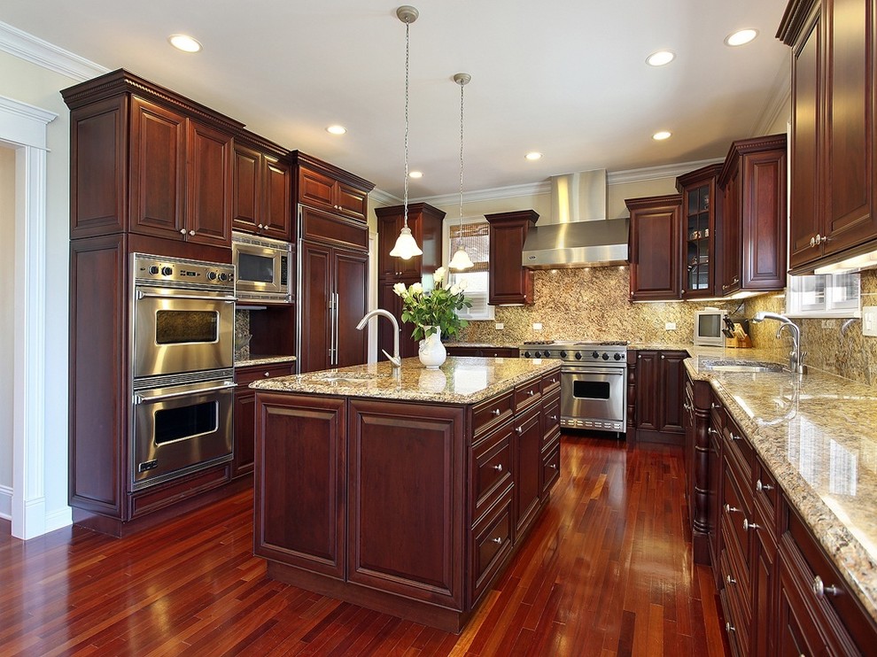 Photo of a large classic u-shaped kitchen/diner in Los Angeles with a submerged sink, shaker cabinets, dark wood cabinets, multi-coloured splashback, stone slab splashback, stainless steel appliances, dark hardwood flooring and an island.
