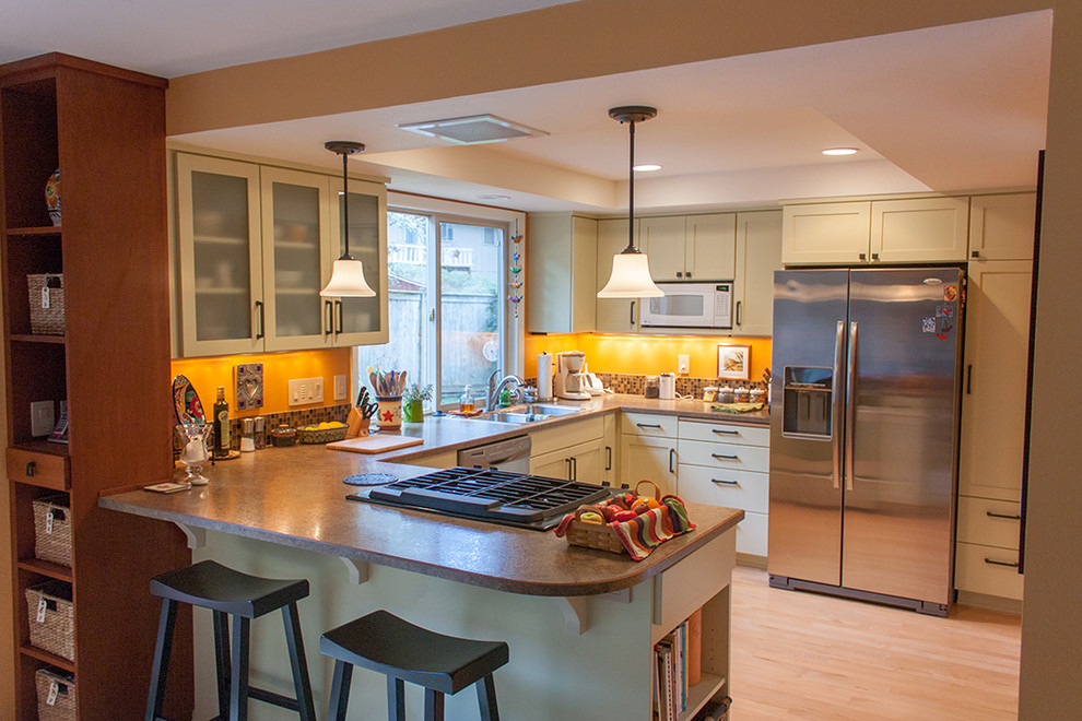 Eat-in kitchen - mid-sized traditional u-shaped light wood floor eat-in kitchen idea in Other with a drop-in sink, flat-panel cabinets, green cabinets, laminate countertops, multicolored backsplash, glass tile backsplash, stainless steel appliances and a peninsula