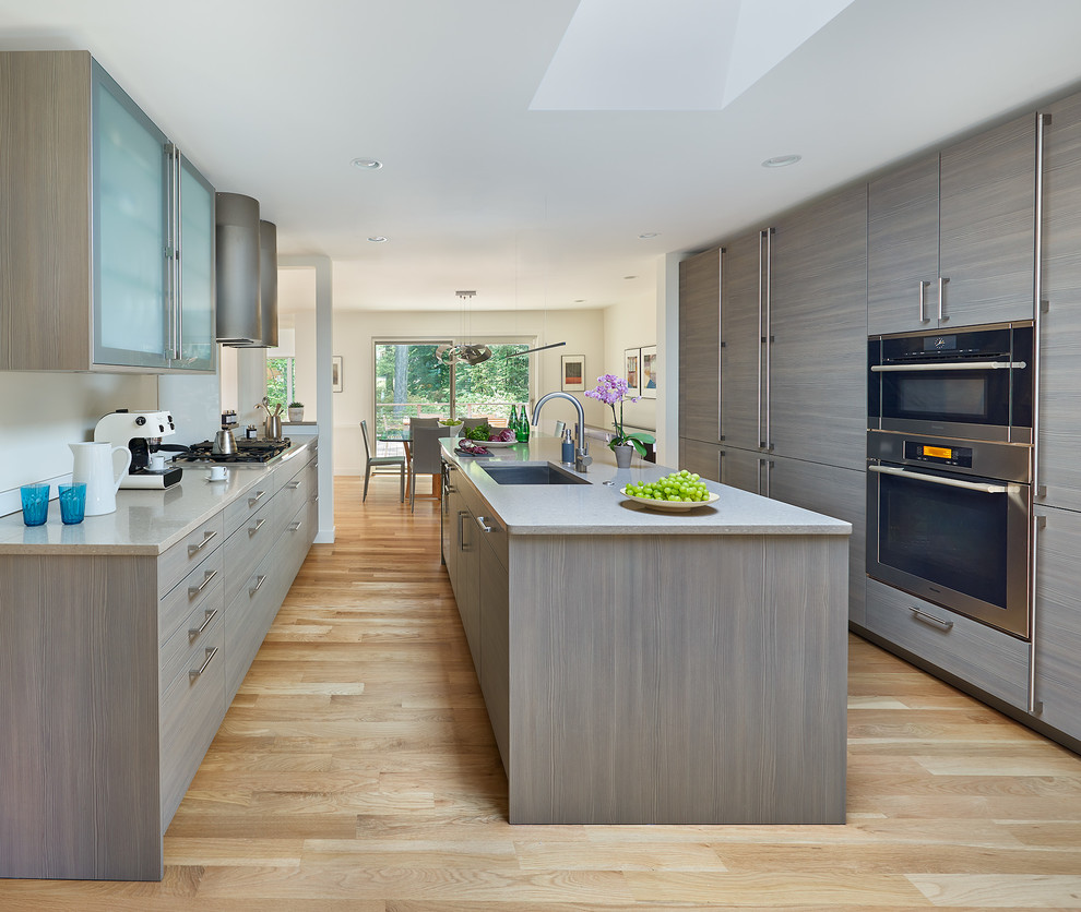 Esempio di una cucina contemporanea con lavello sottopiano, ante lisce, elettrodomestici in acciaio inossidabile, parquet chiaro e top grigio