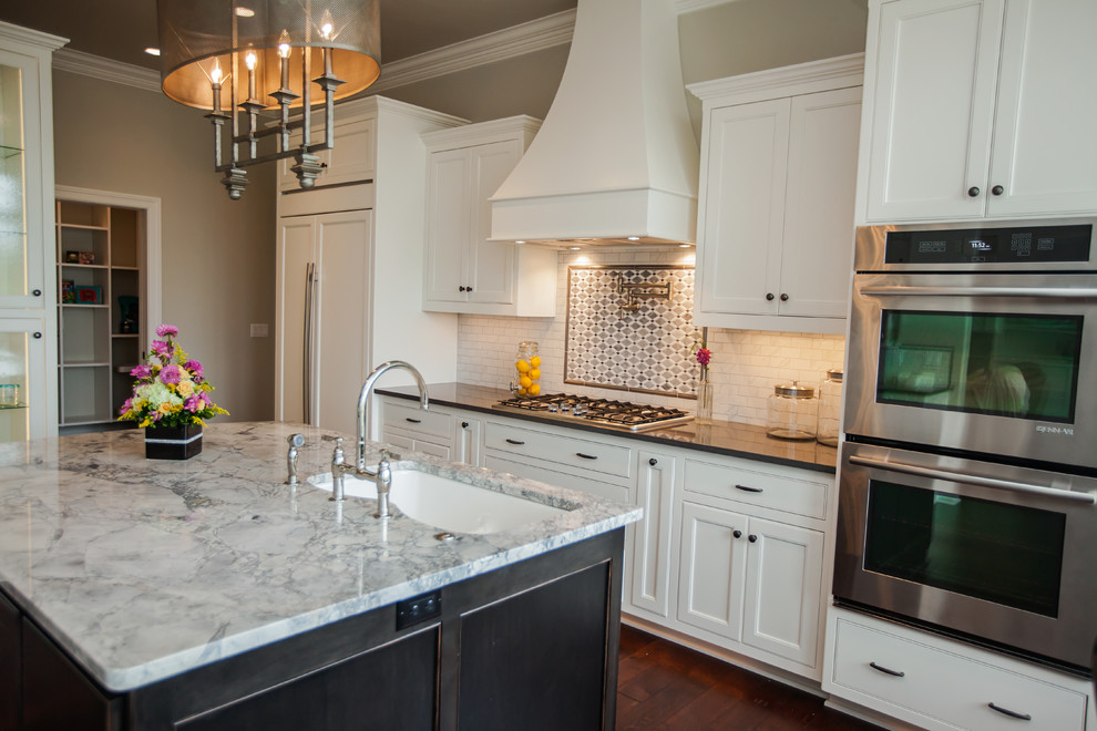Eat-in kitchen - large traditional u-shaped dark wood floor eat-in kitchen idea in Milwaukee with an undermount sink, shaker cabinets, white cabinets, white backsplash, subway tile backsplash, stainless steel appliances and an island