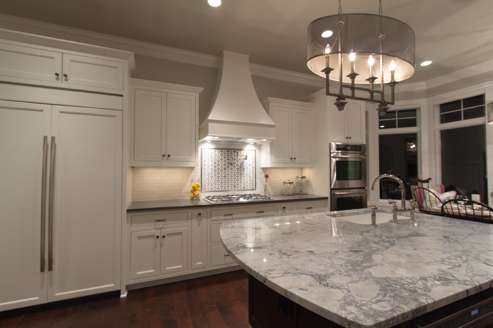 Inspiration for a large transitional u-shaped dark wood floor eat-in kitchen remodel in Milwaukee with an undermount sink, shaker cabinets, white cabinets, white backsplash, subway tile backsplash, stainless steel appliances and an island
