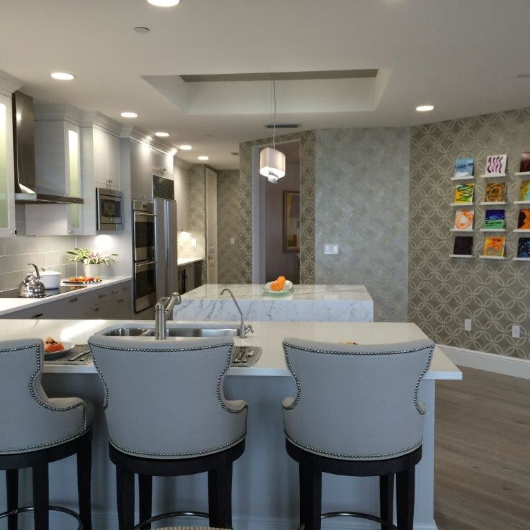 Large transitional light wood floor open concept kitchen photo in Tampa with a double-bowl sink, flat-panel cabinets, white cabinets, quartz countertops, gray backsplash, glass tile backsplash, stainless steel appliances and an island