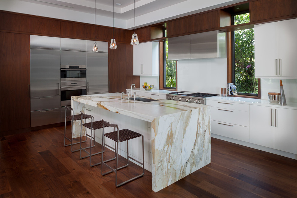 Kitchen - large contemporary u-shaped medium tone wood floor and brown floor kitchen idea in Miami with an undermount sink, flat-panel cabinets, white backsplash, stainless steel appliances, an island, medium tone wood cabinets and marble countertops