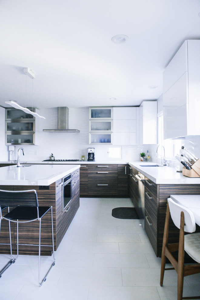 Photo of a medium sized contemporary u-shaped kitchen/diner in San Diego with a submerged sink, flat-panel cabinets, brown cabinets, marble worktops, white splashback, porcelain splashback, stainless steel appliances, ceramic flooring, an island, white floors and white worktops.