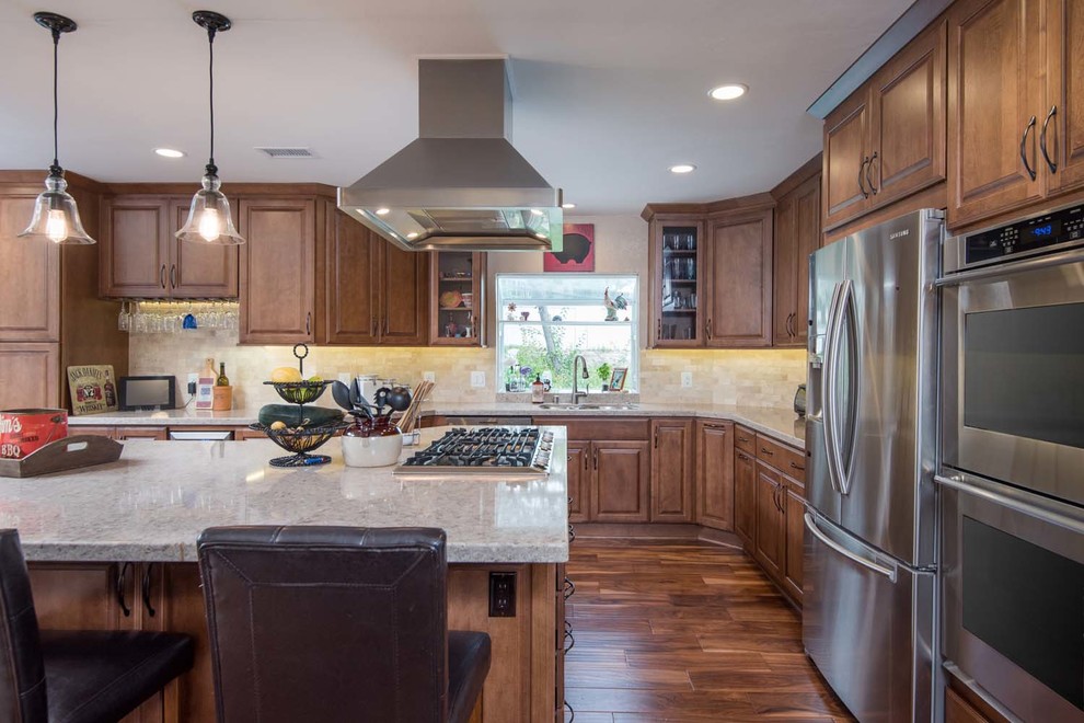 Inspiration for a large timeless u-shaped medium tone wood floor eat-in kitchen remodel in San Diego with an undermount sink, raised-panel cabinets, medium tone wood cabinets, quartz countertops, beige backsplash, mosaic tile backsplash, stainless steel appliances and an island