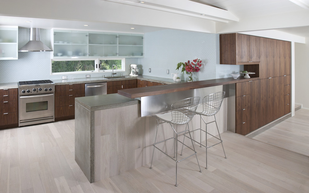 Imagen de cocina moderna con armarios tipo vitrina, electrodomésticos de acero inoxidable, salpicadero azul y barras de cocina