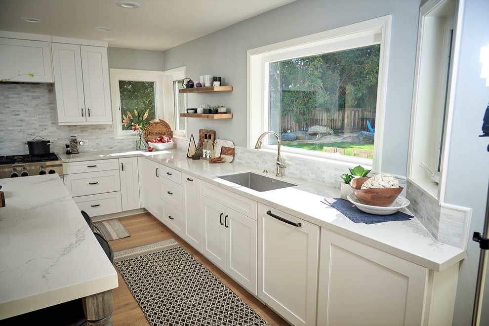 Inspiration for a medium sized farmhouse u-shaped open plan kitchen in San Diego with a submerged sink, recessed-panel cabinets, white cabinets, quartz worktops, white splashback, marble splashback, stainless steel appliances, medium hardwood flooring, an island and beige floors.