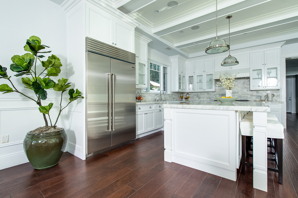 Inspiration for a large coastal l-shaped dark wood floor open concept kitchen remodel in Los Angeles with a double-bowl sink, shaker cabinets, white cabinets, marble countertops, gray backsplash, subway tile backsplash, stainless steel appliances and an island