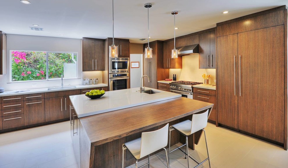 Example of a trendy u-shaped eat-in kitchen design in Los Angeles with an undermount sink, medium tone wood cabinets, quartz countertops, white backsplash, porcelain backsplash and stainless steel appliances
