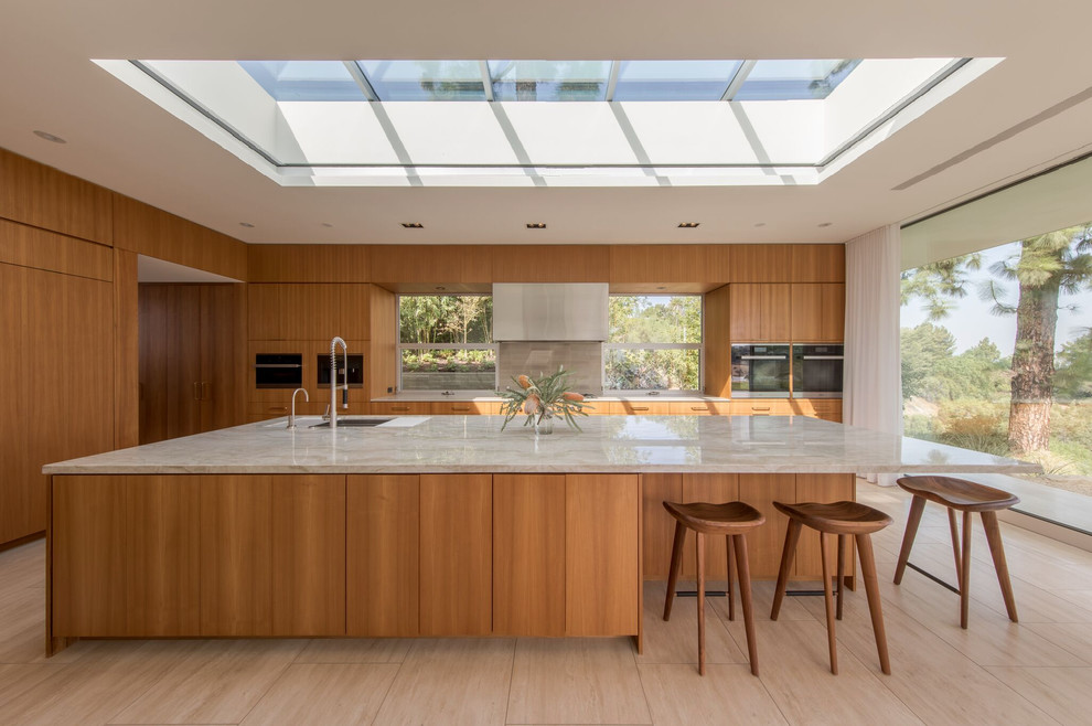 Kitchen - mid-century modern beige floor kitchen idea in Los Angeles with an undermount sink, flat-panel cabinets, medium tone wood cabinets, window backsplash, an island and gray countertops