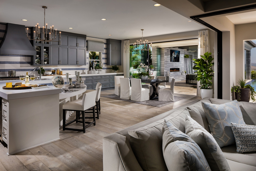 This is an example of a large classic single-wall open plan kitchen in San Diego with an island, recessed-panel cabinets, grey cabinets, composite countertops, light hardwood flooring, brown floors and white worktops.