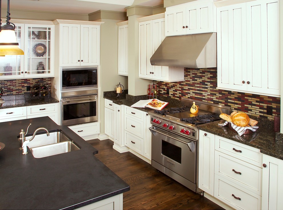 Bild på ett mellanstort amerikanskt svart svart kök, med en undermonterad diskho, skåp i shakerstil, vita skåp, bänkskiva i kvarts, flerfärgad stänkskydd, stänkskydd i stickkakel, integrerade vitvaror, mörkt trägolv, en köksö och brunt golv