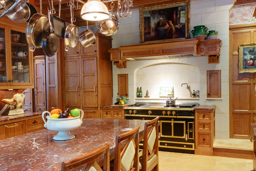 Foto på ett stort vintage kök, med skåp i mellenmörkt trä, marmorbänkskiva, vitt stänkskydd, stänkskydd i stenkakel, svarta vitvaror, kalkstensgolv och en köksö
