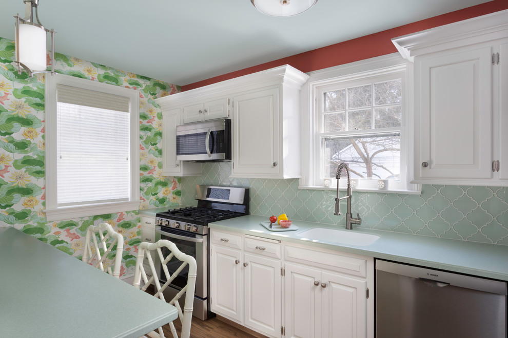 他の地域にある小さなトラディショナルスタイルのおしゃれなII型キッチン (一体型シンク、レイズドパネル扉のキャビネット、白いキャビネット、人工大理石カウンター、緑のキッチンパネル、ガラスタイルのキッチンパネル、シルバーの調理設備、クッションフロア、茶色い床、緑のキッチンカウンター) の写真