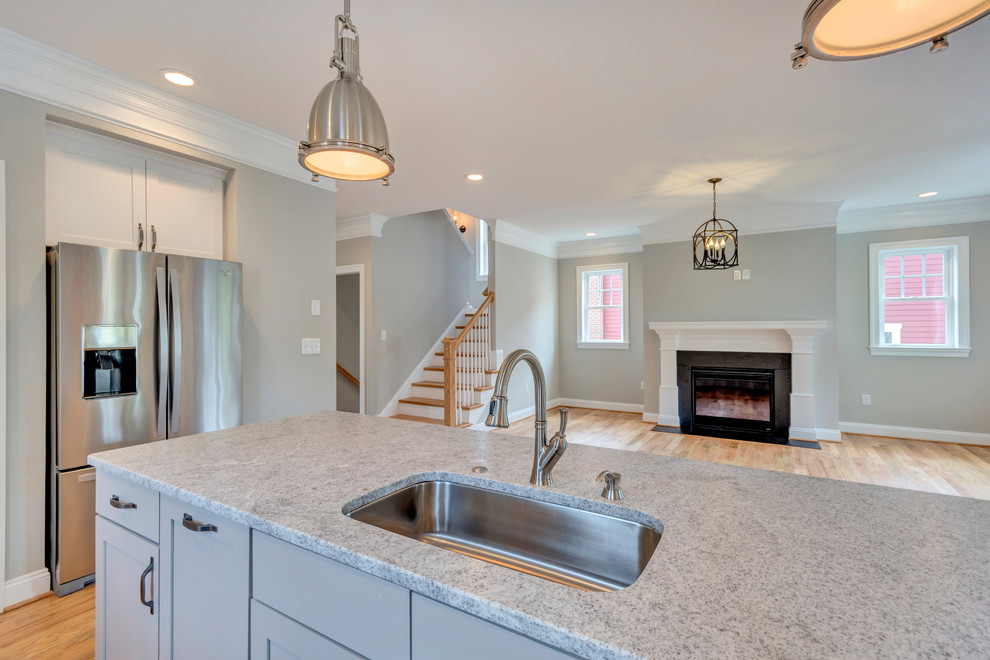 Ispirazione per una grande cucina american style con lavello da incasso, ante con riquadro incassato, ante bianche, top in granito, paraspruzzi bianco, paraspruzzi con piastrelle in ceramica, elettrodomestici in acciaio inossidabile, pavimento in legno massello medio e pavimento marrone
