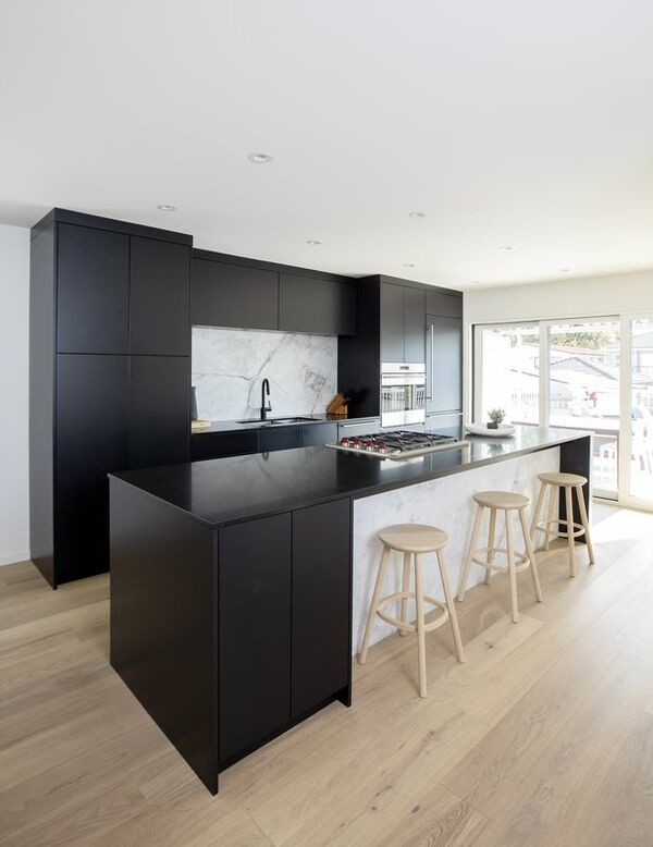 This is an example of a medium sized modern single-wall kitchen/diner in Vancouver with a submerged sink, flat-panel cabinets, black cabinets, composite countertops, white splashback, marble splashback, integrated appliances, light hardwood flooring, an island, beige floors and black worktops.