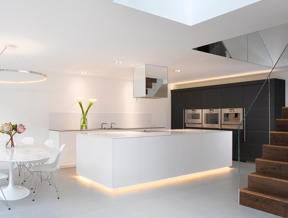 Moderne Wohnküche mit flächenbündigen Schrankfronten, Küchenrückwand in Weiß, Küchengeräten aus Edelstahl und Kücheninsel in London