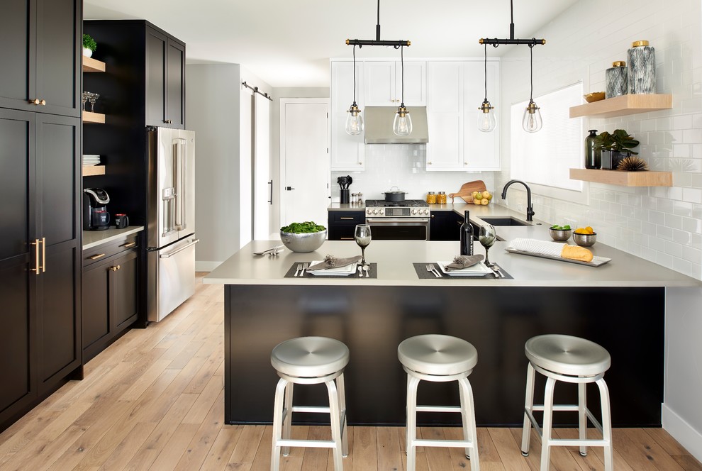 Mid-sized transitional u-shaped light wood floor kitchen photo in Denver with a single-bowl sink, shaker cabinets, black cabinets, quartz countertops, white backsplash, stainless steel appliances, a peninsula, gray countertops and subway tile backsplash