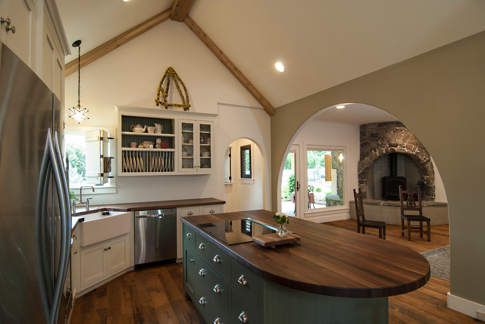 Inspiration for a medium sized country kitchen/diner in Charlotte with shaker cabinets, wood worktops, dark hardwood flooring, an island, a belfast sink and stainless steel appliances.