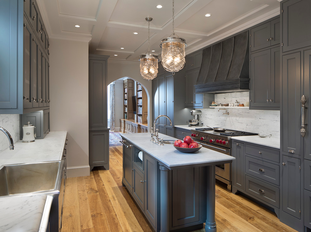 Eat-in kitchen - mid-sized traditional l-shaped medium tone wood floor eat-in kitchen idea in San Francisco with a farmhouse sink, recessed-panel cabinets, gray cabinets, marble countertops, white backsplash, stone tile backsplash, stainless steel appliances and an island