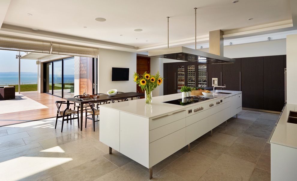 Стильный дизайн: параллельная кухня в современном стиле с обеденным столом, островом, врезной мойкой, плоскими фасадами, техникой под мебельный фасад и черно-белыми фасадами - последний тренд