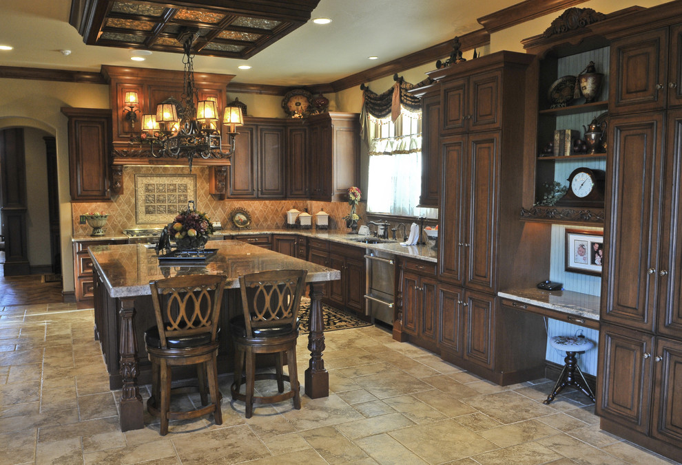 Example of a large ornate l-shaped travertine floor enclosed kitchen design in Oklahoma City with an undermount sink, beaded inset cabinets, dark wood cabinets, granite countertops, beige backsplash, stone tile backsplash, stainless steel appliances and an island