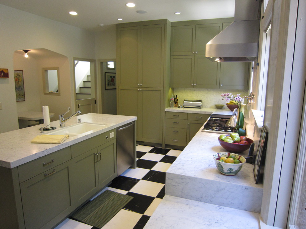Inredning av ett klassiskt kök, med en rustik diskho, skåp i shakerstil, gröna skåp, marmorbänkskiva, vitt stänkskydd, stänkskydd i sten, rostfria vitvaror, marmorgolv och en köksö