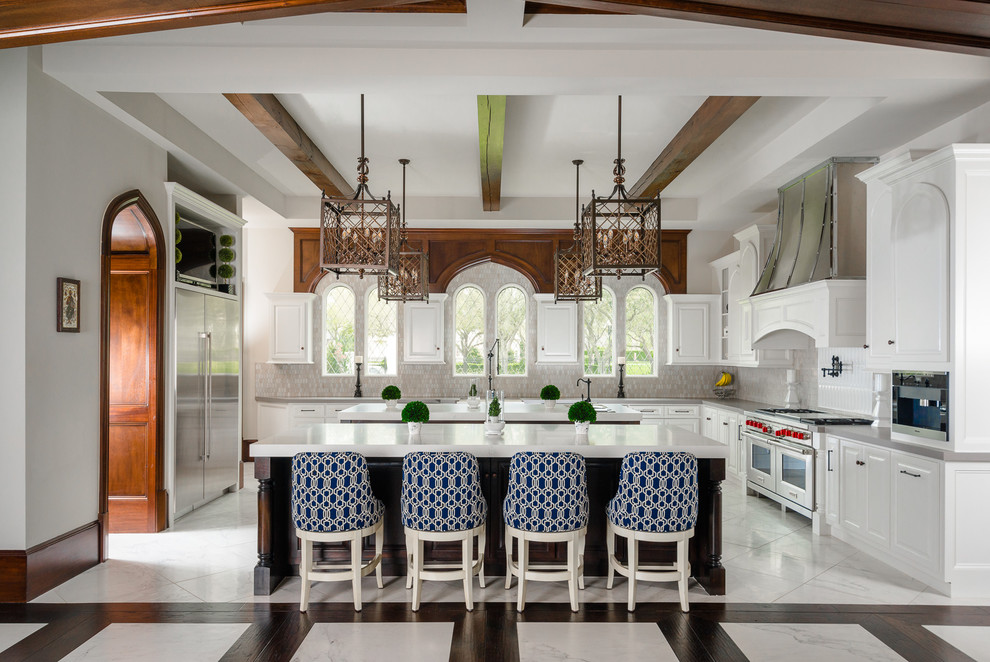 Inspiration for a large mediterranean u-shaped white floor open concept kitchen remodel in Houston with shaker cabinets, white cabinets, beige backsplash, stainless steel appliances, two islands and white countertops