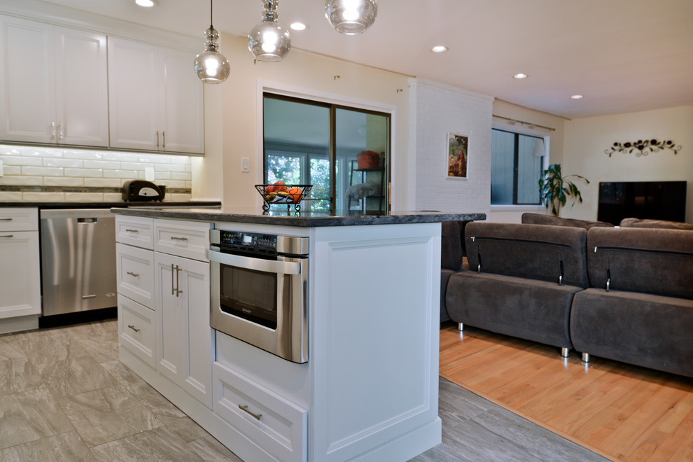 Esempio di una cucina minimal di medie dimensioni con ante lisce, ante bianche, top in granito, paraspruzzi bianco, elettrodomestici in acciaio inossidabile, pavimento grigio e top grigio