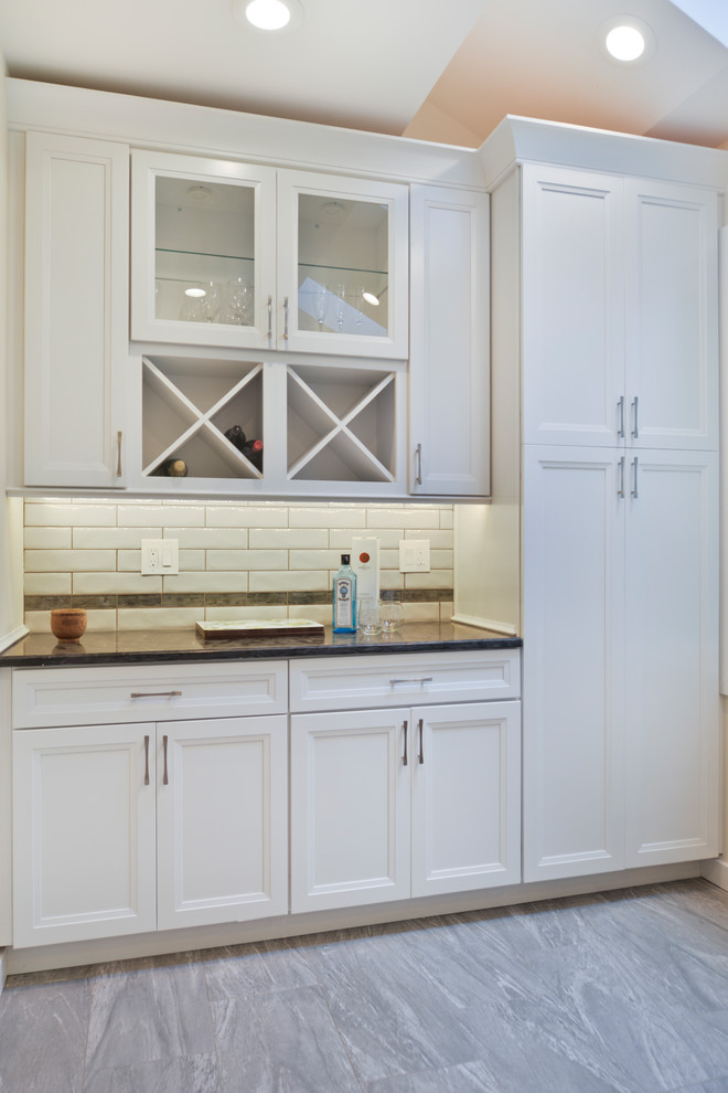 Diseño de cocina comedor contemporánea de tamaño medio con armarios con paneles lisos, puertas de armario blancas, encimera de granito, salpicadero blanco, electrodomésticos de acero inoxidable, una isla, suelo gris y encimeras grises