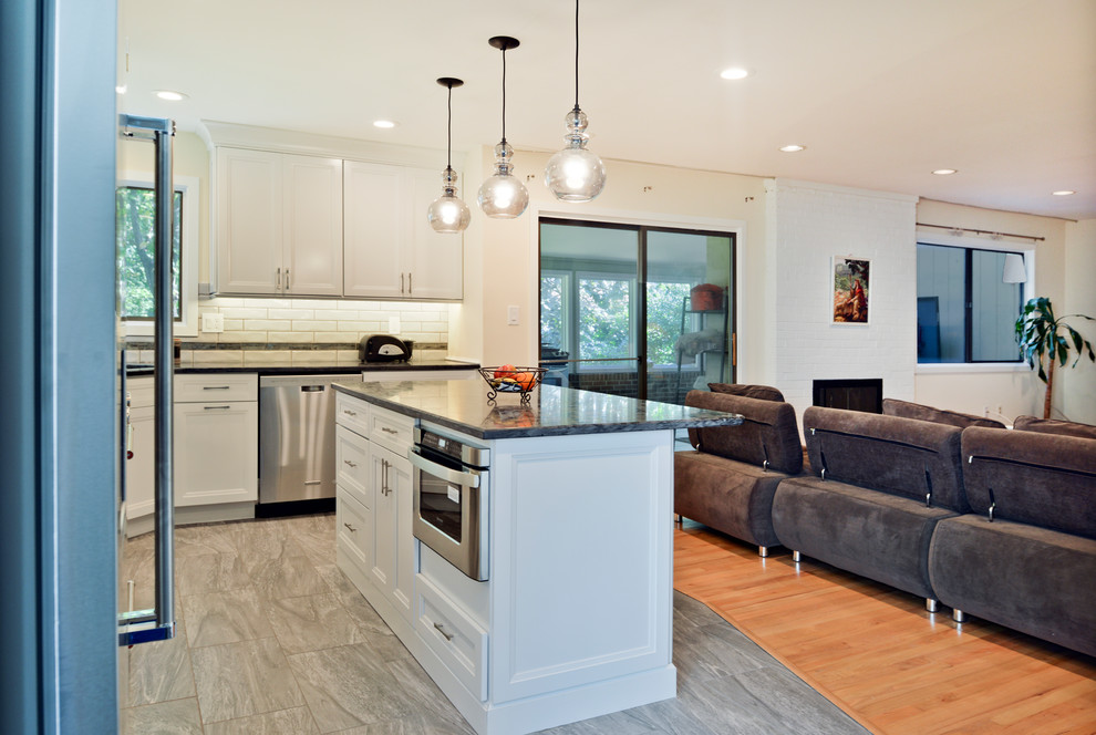 Inredning av ett modernt mellanstort grå grått kök och matrum, med släta luckor, vita skåp, granitbänkskiva, vitt stänkskydd, rostfria vitvaror, en köksö och grått golv