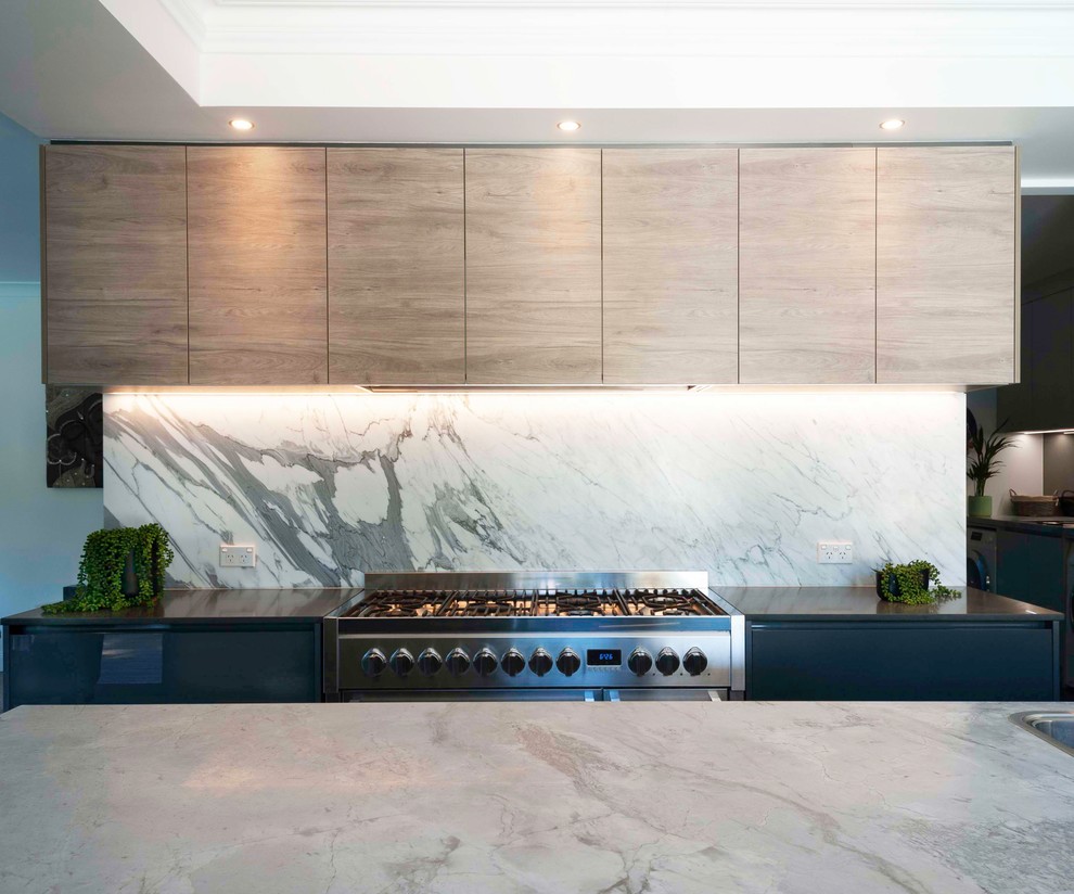 This is an example of a large contemporary galley open plan kitchen in Sydney with a built-in sink, marble worktops, stone slab splashback, black appliances and an island.