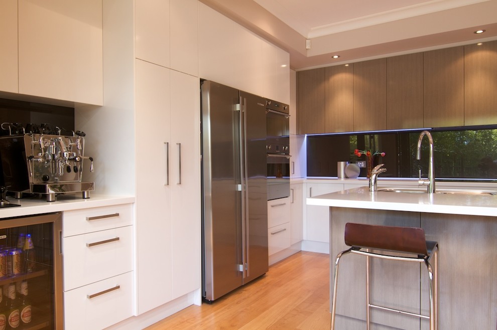 Idéer för att renovera ett mellanstort funkis kök, med en trippel diskho, vita skåp, glaspanel som stänkskydd, rostfria vitvaror, en köksö, släta luckor, bänkskiva i koppar, svart stänkskydd och ljust trägolv
