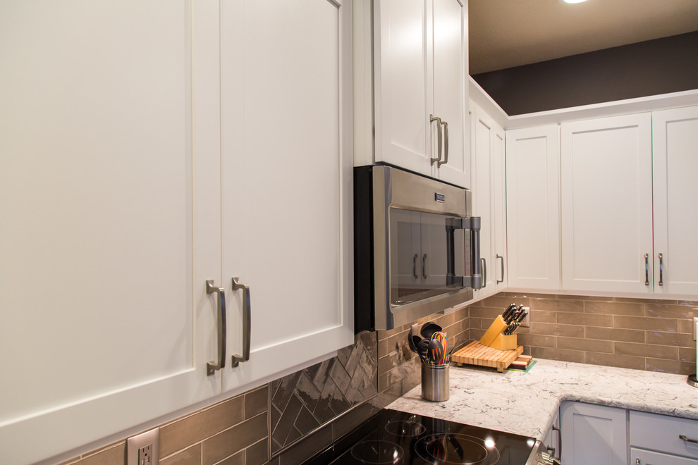 Photo of a medium sized classic l-shaped open plan kitchen in Portland with a double-bowl sink, flat-panel cabinets, white cabinets, engineered stone countertops, beige splashback, ceramic splashback, stainless steel appliances, medium hardwood flooring and an island.