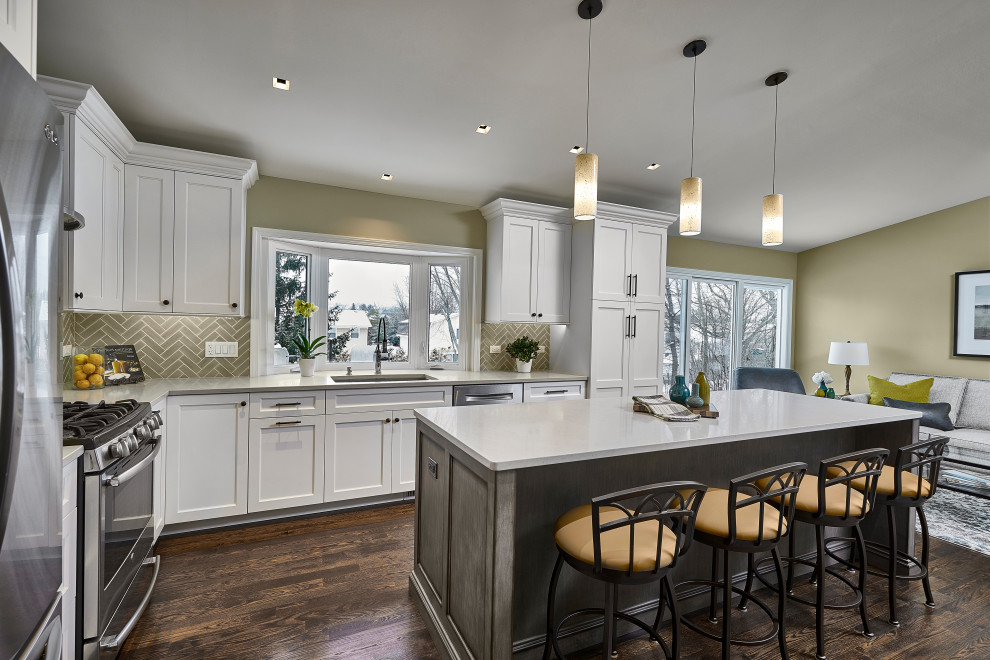 Large elegant l-shaped dark wood floor and brown floor open concept kitchen photo in Chicago with an undermount sink, recessed-panel cabinets, white cabinets, quartz countertops, gray backsplash, ceramic backsplash, stainless steel appliances, an island and white countertops