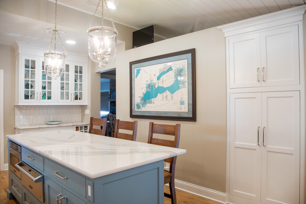 Large transitional u-shaped medium tone wood floor, brown floor and shiplap ceiling eat-in kitchen photo in Milwaukee with an undermount sink, recessed-panel cabinets, white cabinets, quartz countertops, white backsplash, porcelain backsplash, stainless steel appliances, an island and white countertops