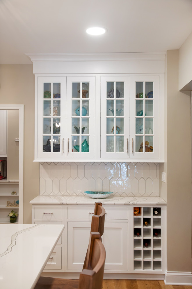 Inspiration för stora klassiska vitt kök, med en undermonterad diskho, luckor med infälld panel, vita skåp, bänkskiva i kvarts, vitt stänkskydd, stänkskydd i porslinskakel, rostfria vitvaror, mellanmörkt trägolv, en köksö och brunt golv
