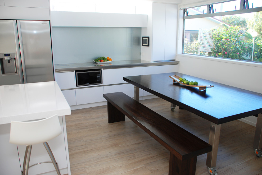 Zweizeilige, Mittelgroße Moderne Küche mit Unterbauwaschbecken, flächenbündigen Schrankfronten, weißen Schränken, Küchengeräten aus Edelstahl und Kücheninsel in Napier-Hastings
