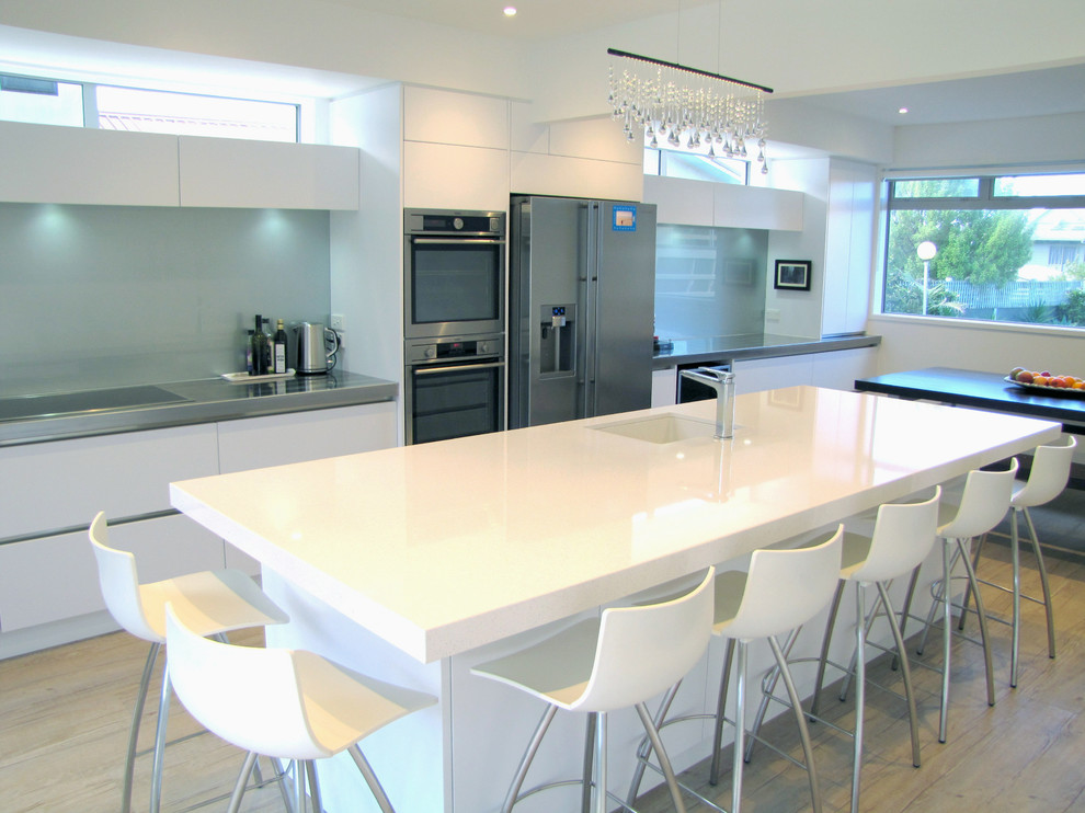 Zweizeilige, Mittelgroße Moderne Küche mit Unterbauwaschbecken, flächenbündigen Schrankfronten, weißen Schränken, Küchengeräten aus Edelstahl und Kücheninsel in Napier-Hastings