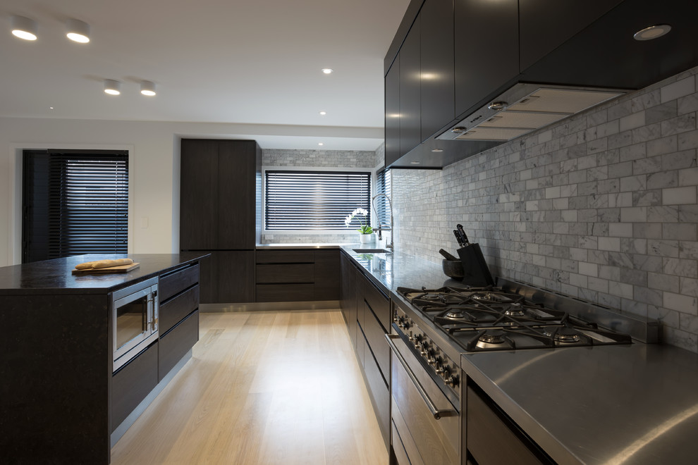 Exempel på ett stort modernt kök, med en köksö, en integrerad diskho, släta luckor, skåp i mörkt trä, bänkskiva i rostfritt stål, grått stänkskydd, stänkskydd i keramik, rostfria vitvaror, ljust trägolv och gult golv